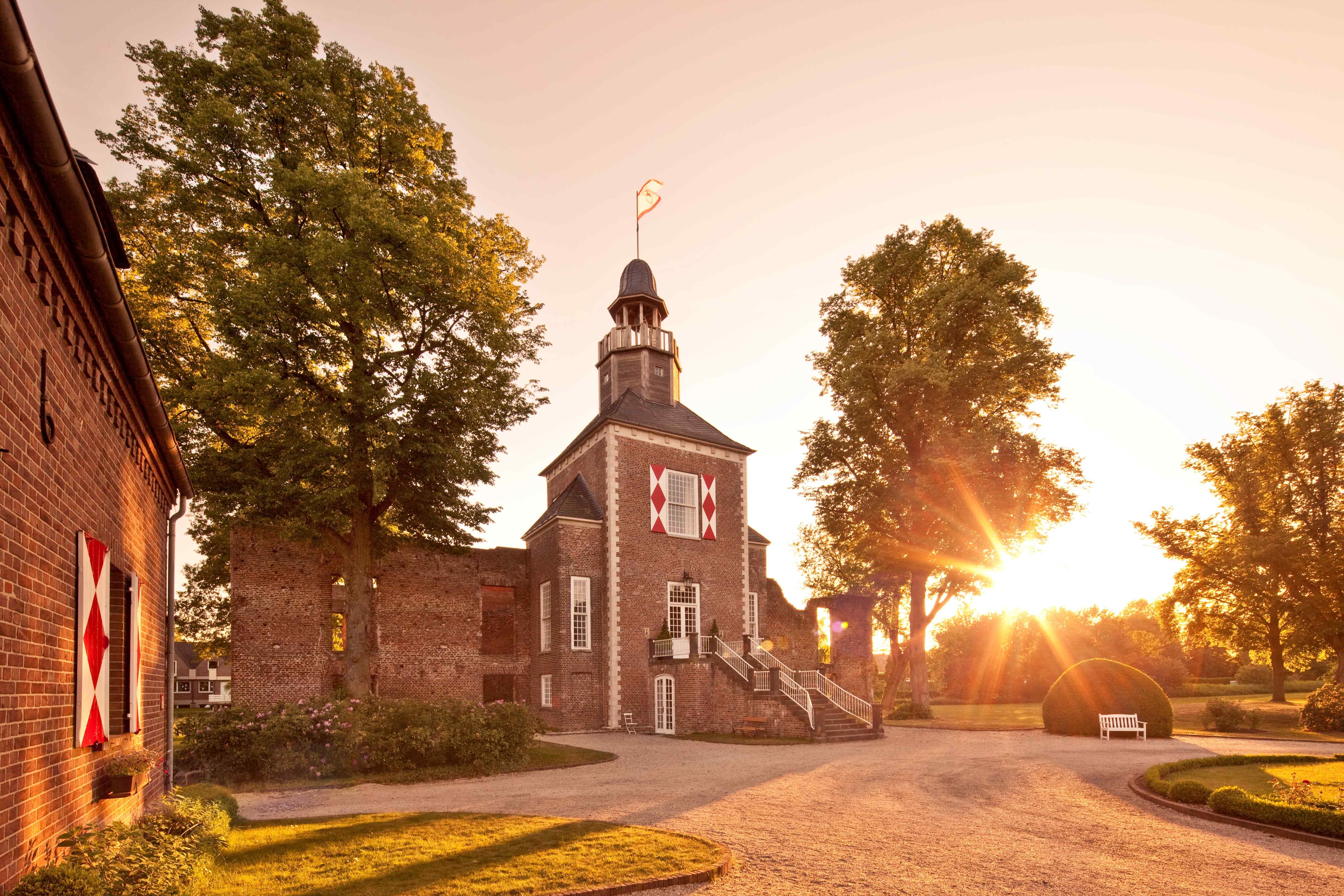 Auf einem Schlossturm weht eine Fahne im Licht der untergehenden Sonne