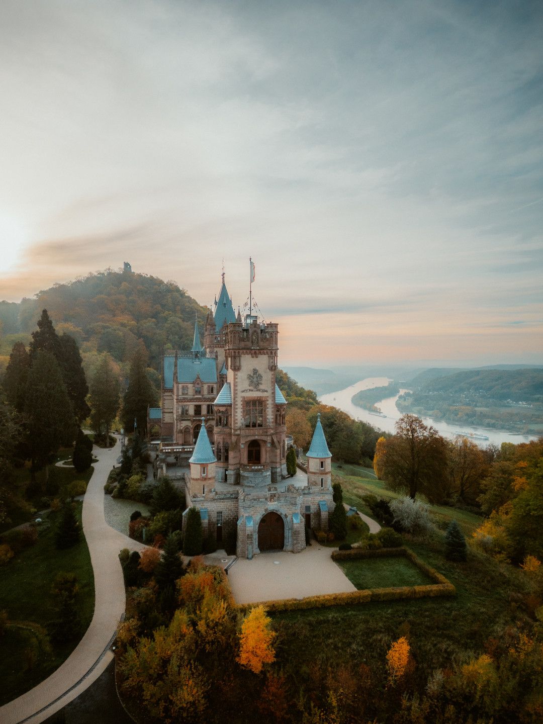 Schloss Drachenburg mit Blick auf den Rhein Richtung Bad Honnef, im Hintergrund ist der Drachenfels zu sehen.