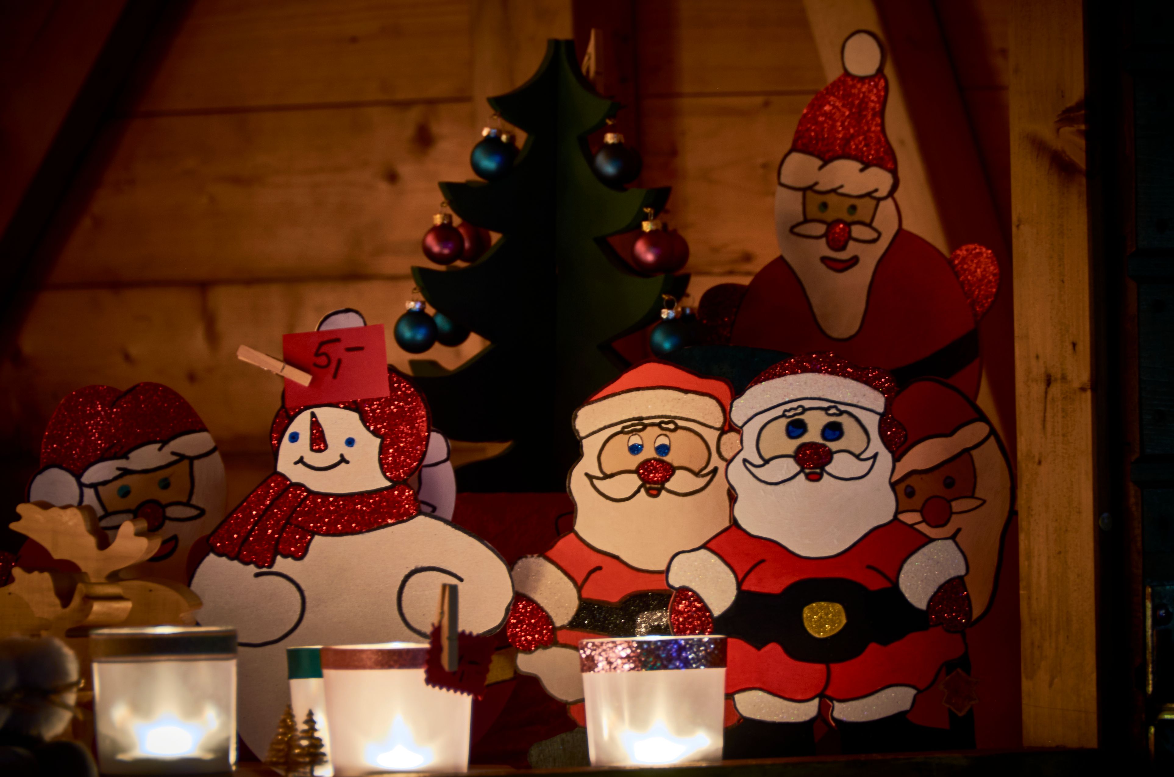 Wooden figures of Santa Clauses and a snowman at a Christmas market stall.