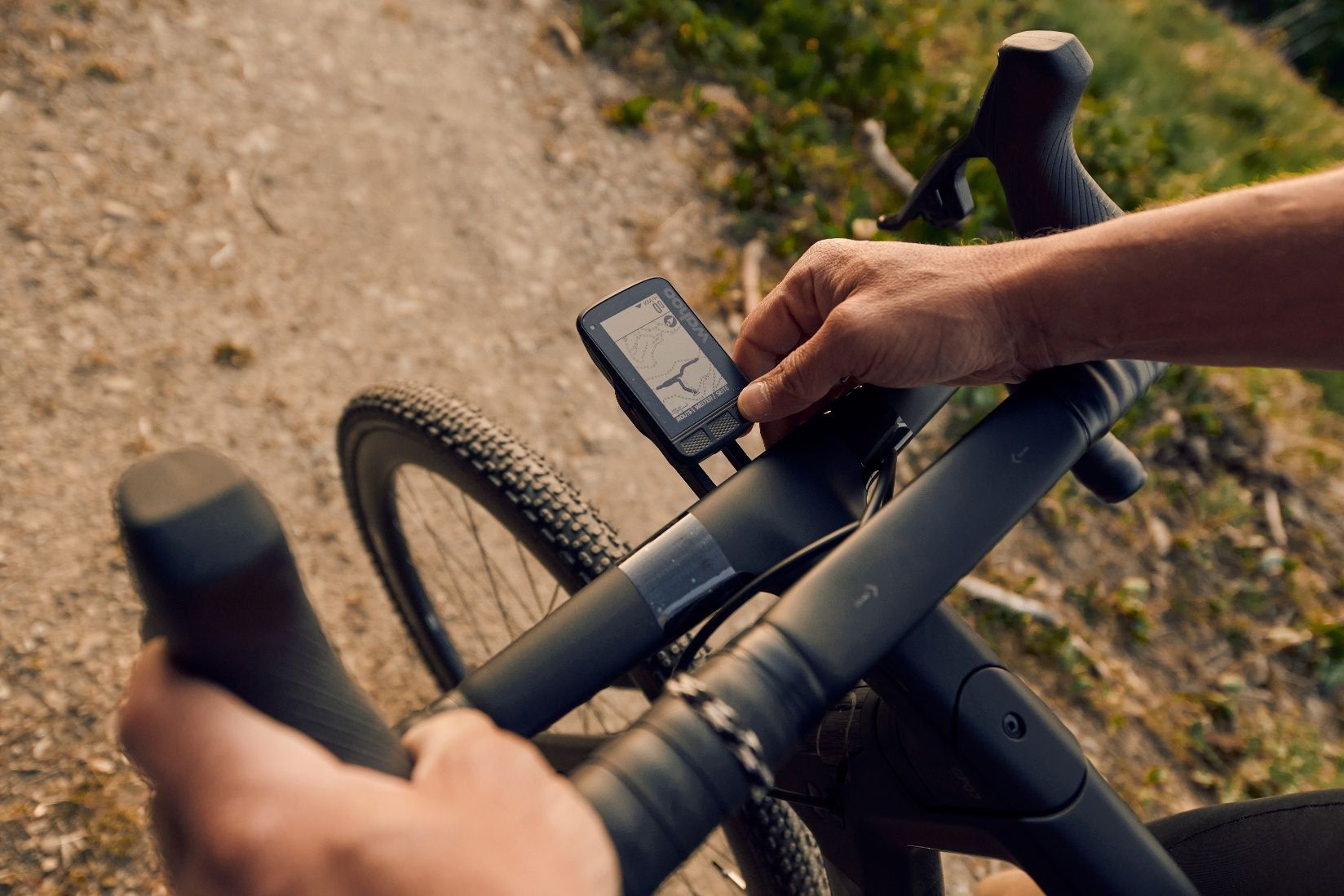 Close-up of a gravel bike with navigation device on a gravel road.
