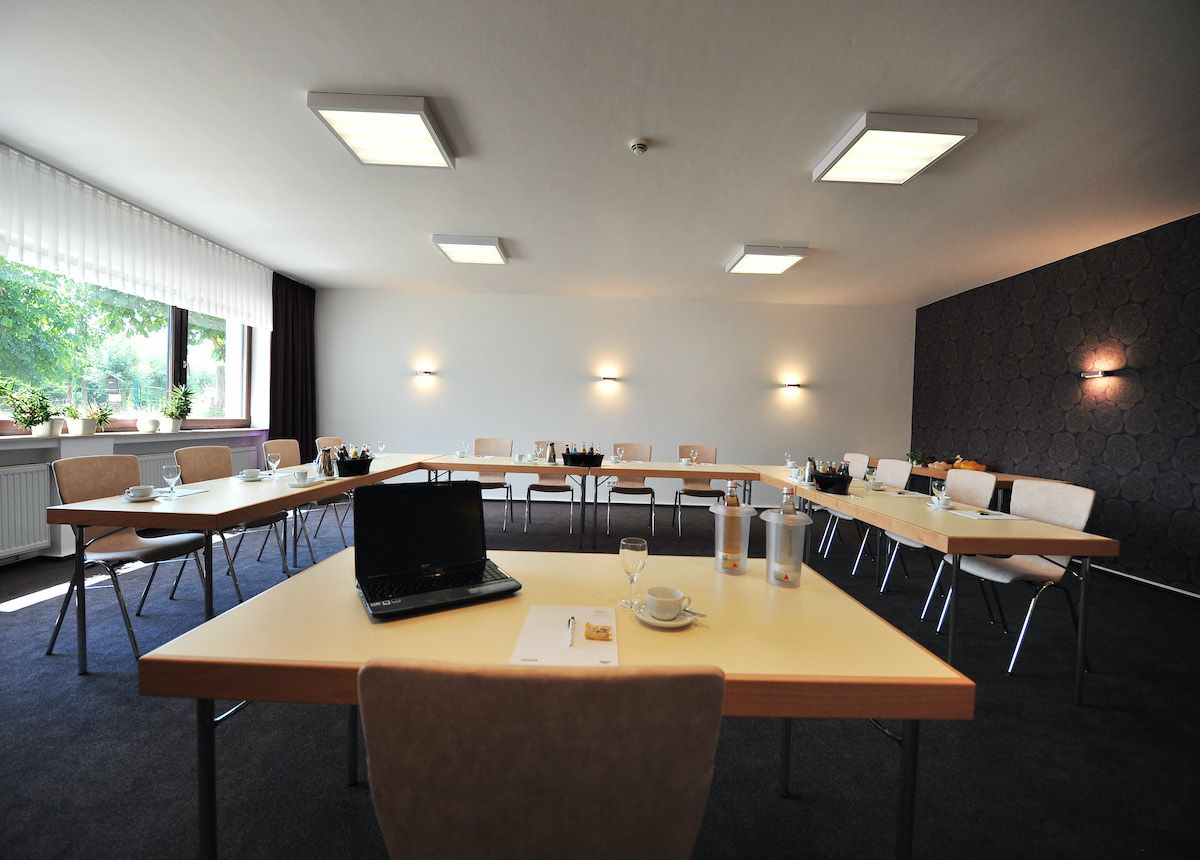 Meyer conference room in Kalkar with U-shaped table arrangement, laptop, drinks and notepaper on the tables.