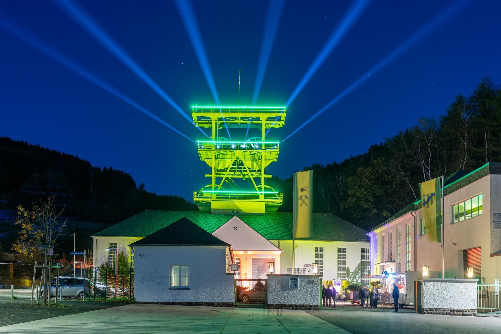An illuminated winding tower in Lennestadt shines in green light at night.