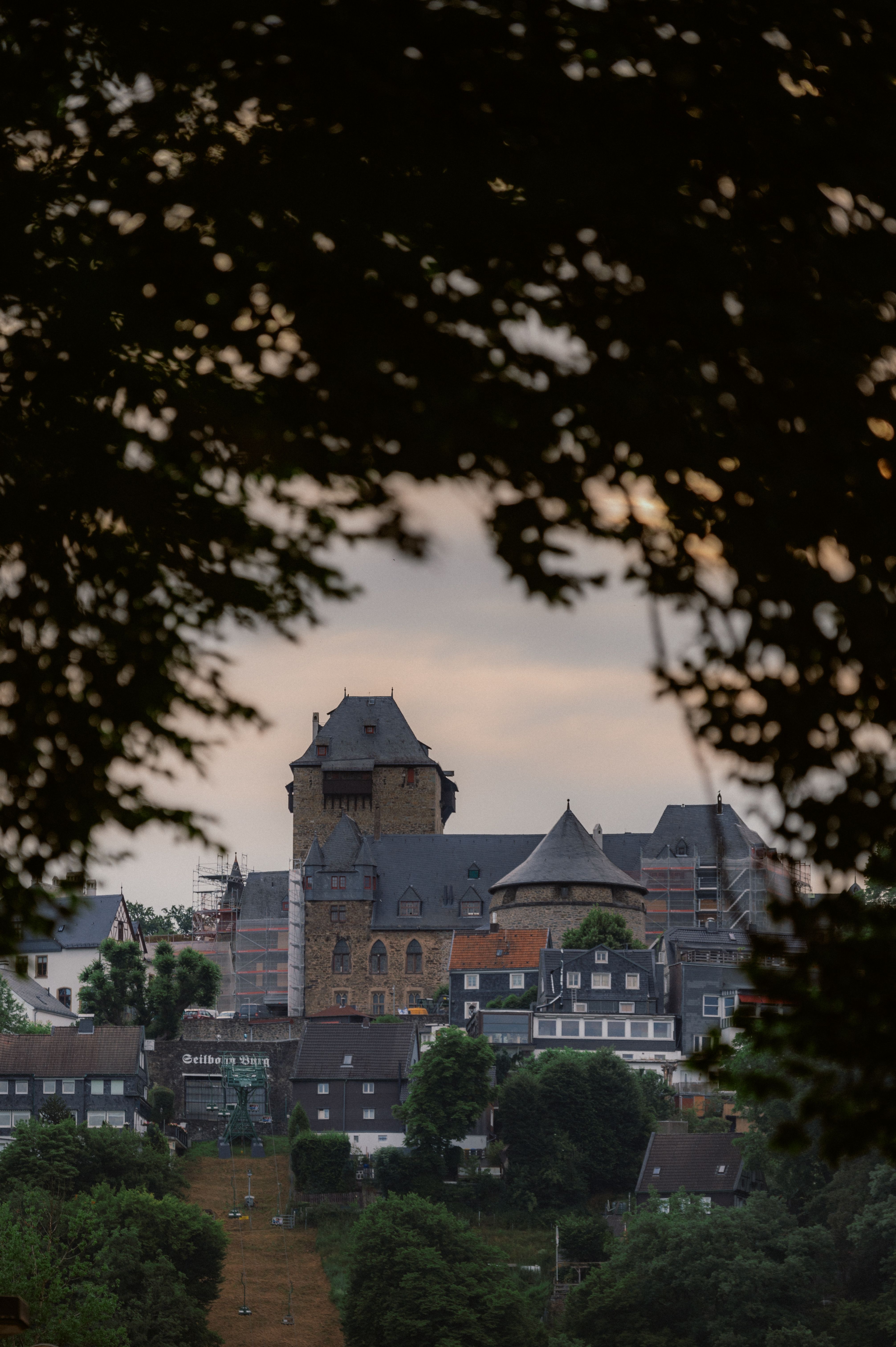 The keep of Burg Castle rises up between the trees towards the sky