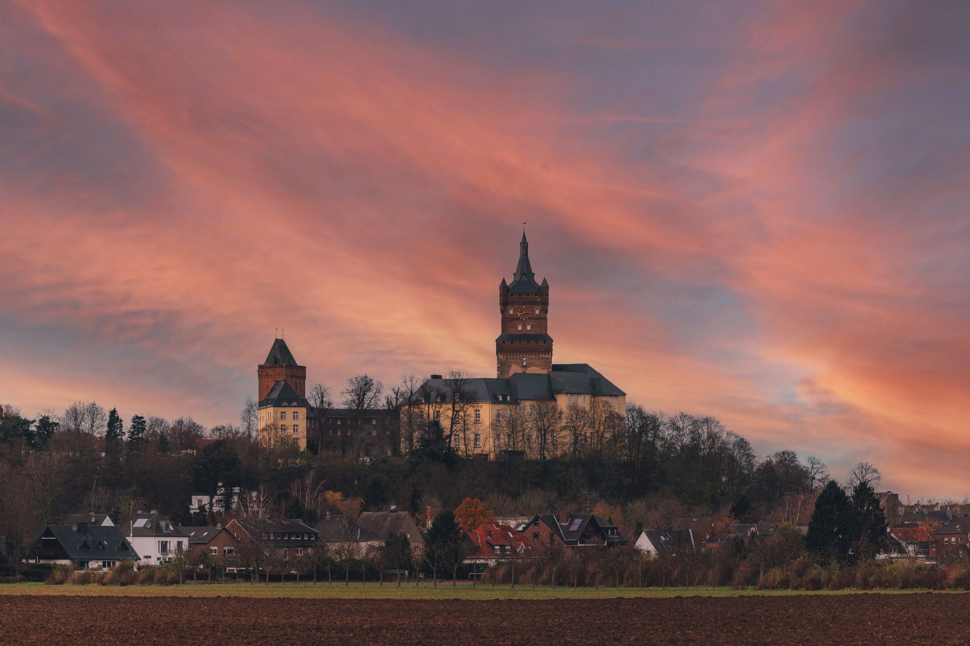 Schwanenburg ragt über Häuser von Kleve in roten Morgenhimmel
