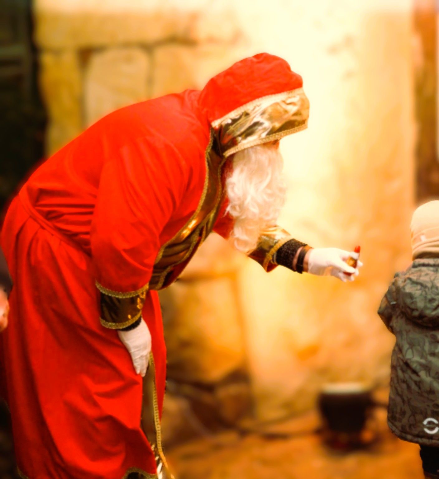St. Nicholas in a red robe hands a gift to a child at the Tecklenburg St. Nicholas market. 