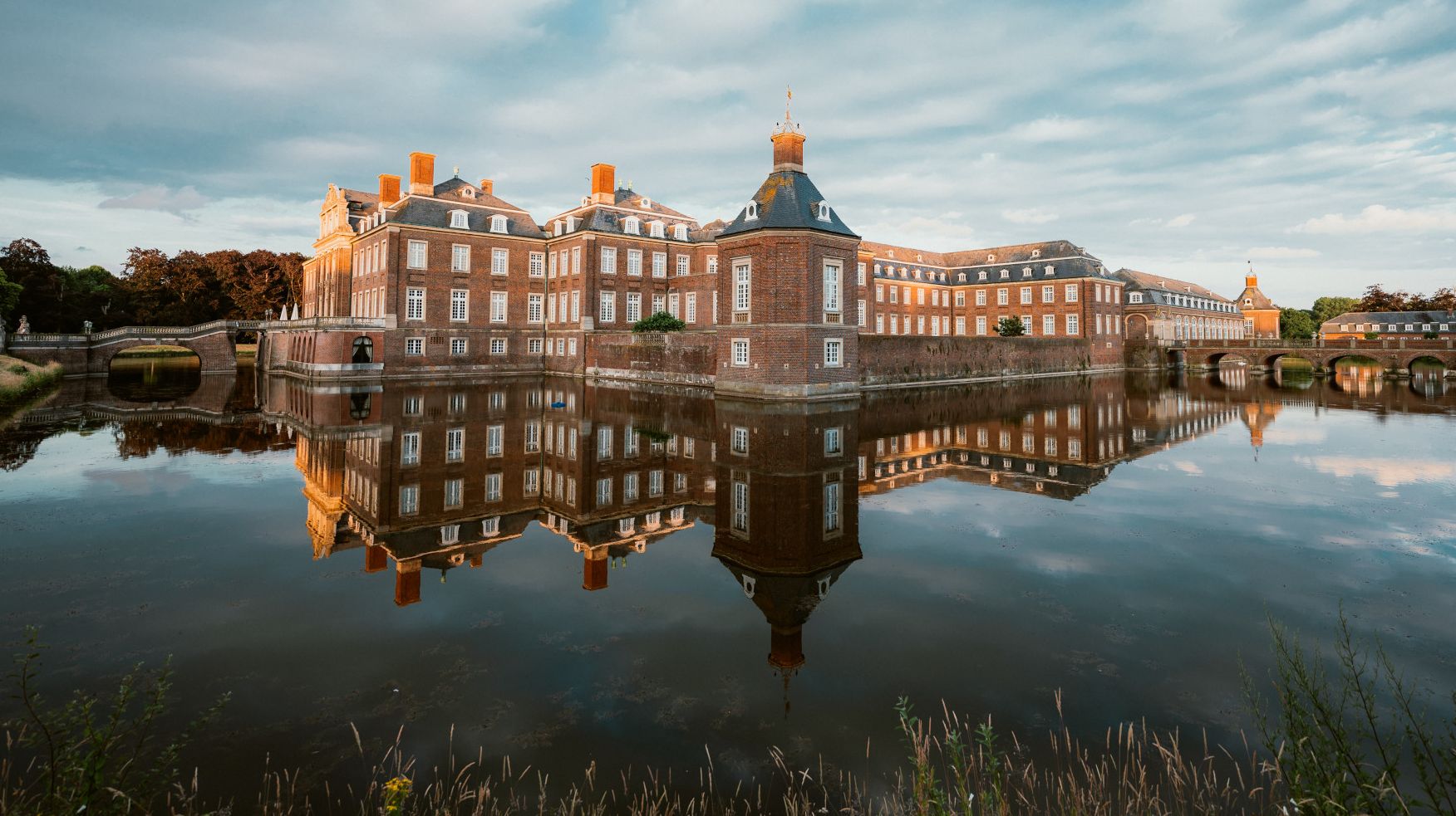 Schloss und Wolken-Himmel spiegeln sich im Wasser  