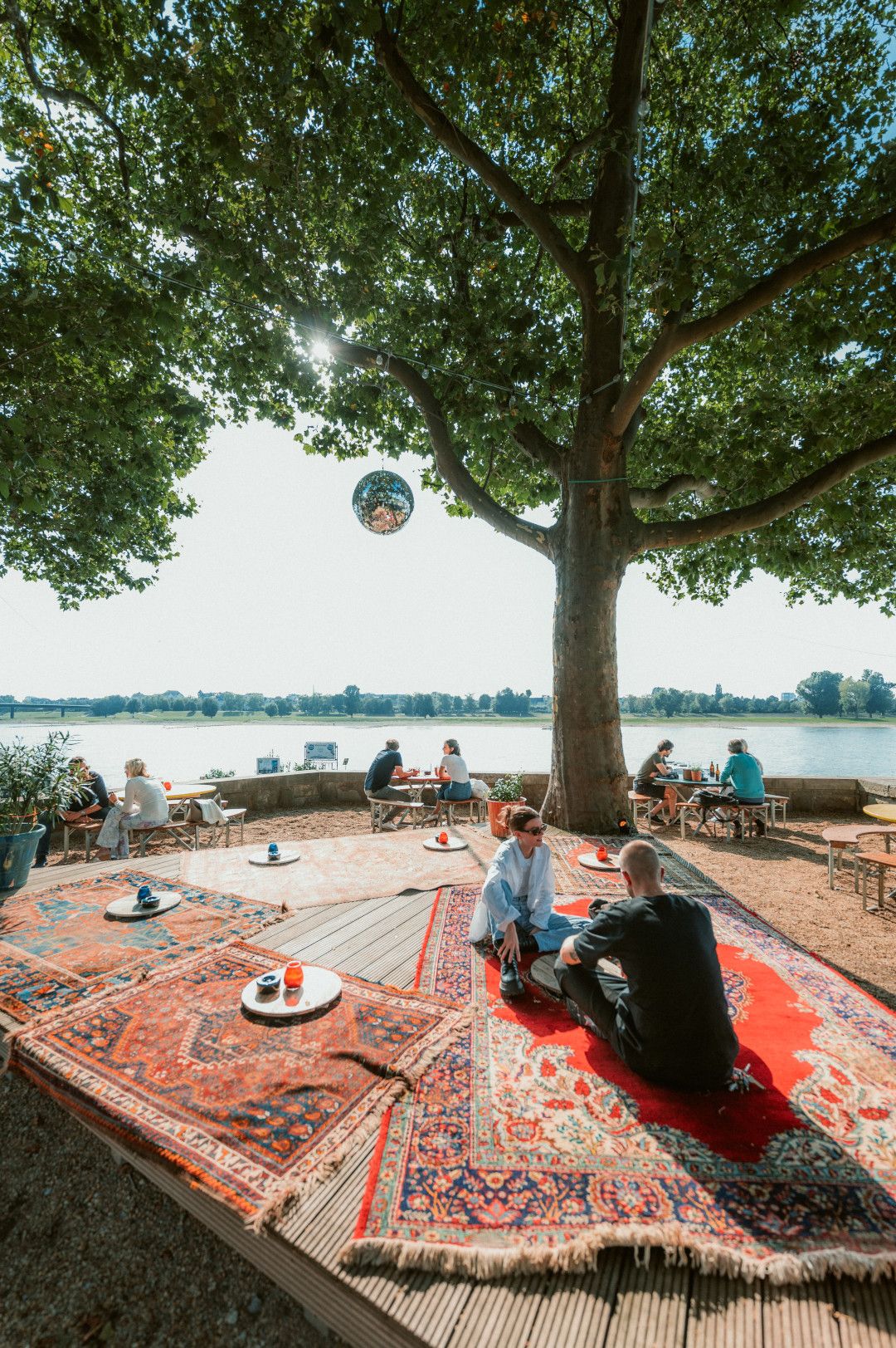 Seating by the water under a tree at Three Little Birds 