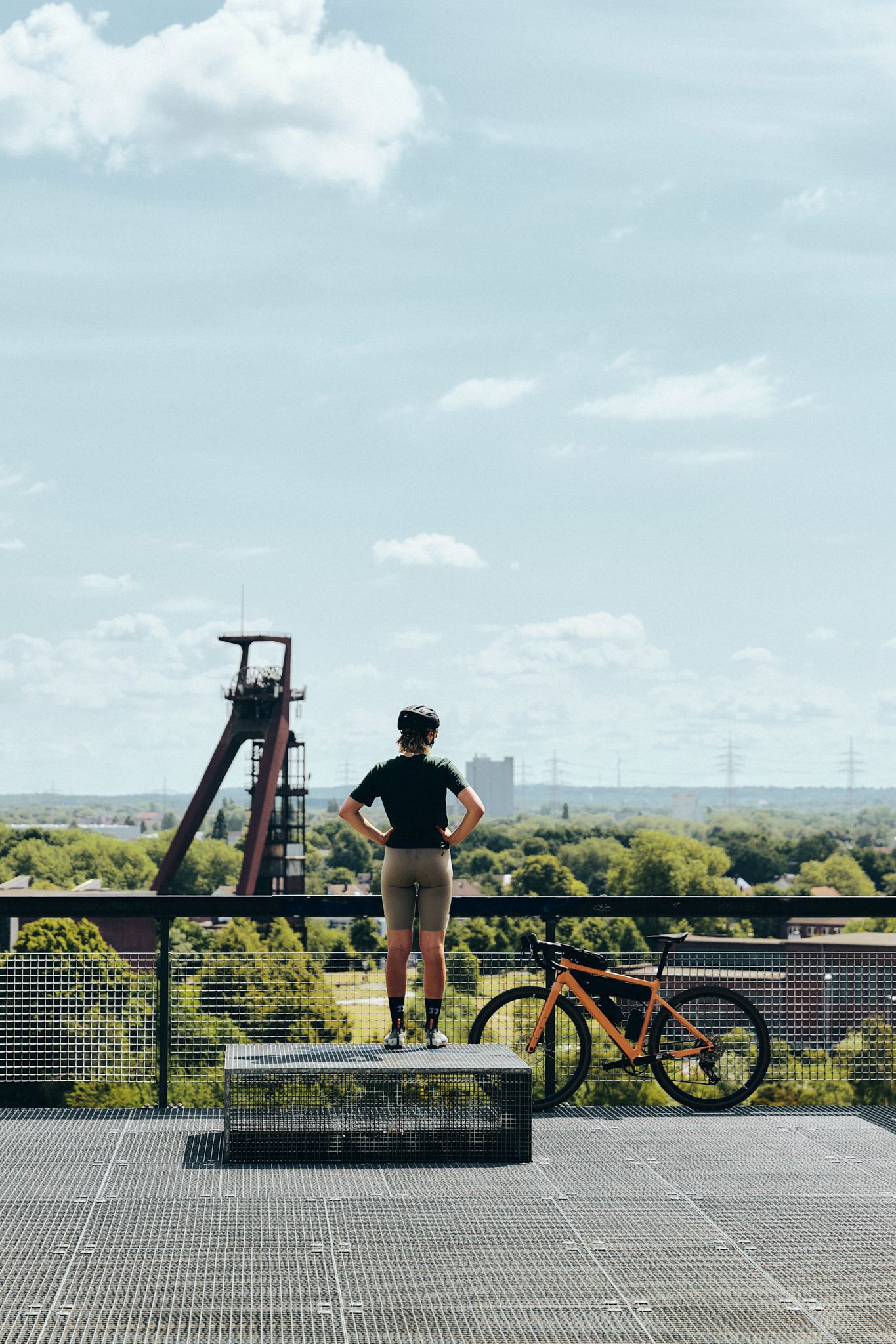 A person wearing a bicycle helmet stands on a platform in Nordsternpark and looks out over the Ruhr region