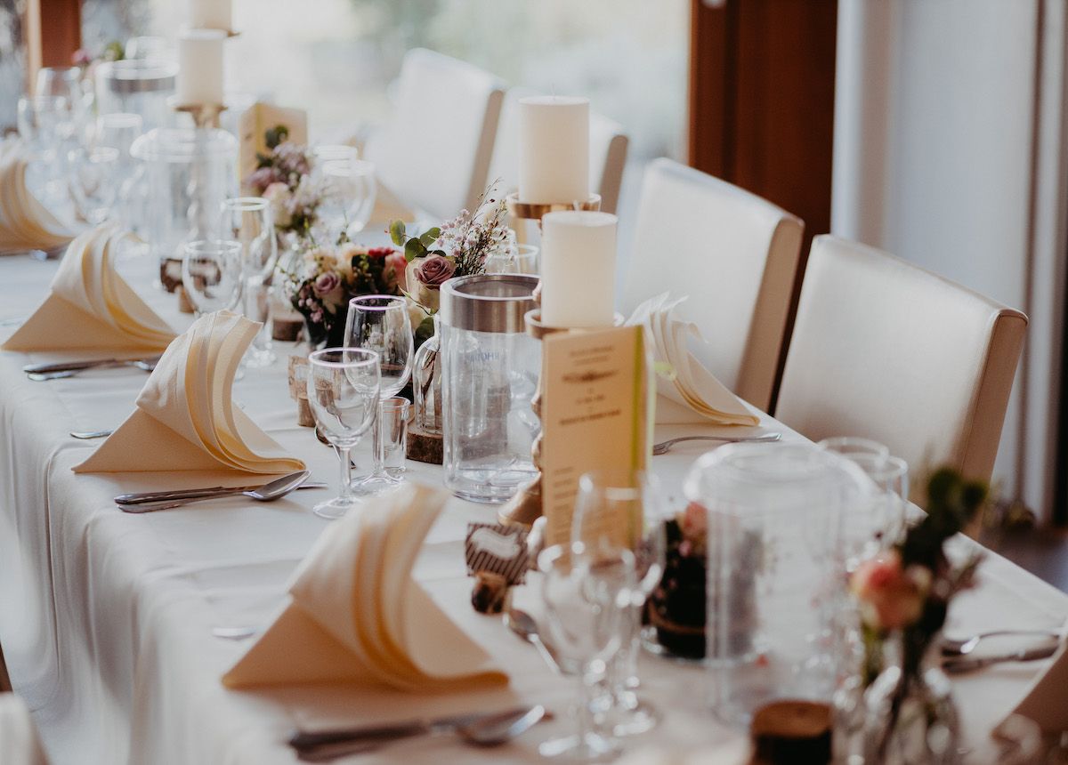 Elegant table at Landhaus Beckmann Restaurant in Kalkar with white tablecloth, folded napkins, glasses and flower arrangement.