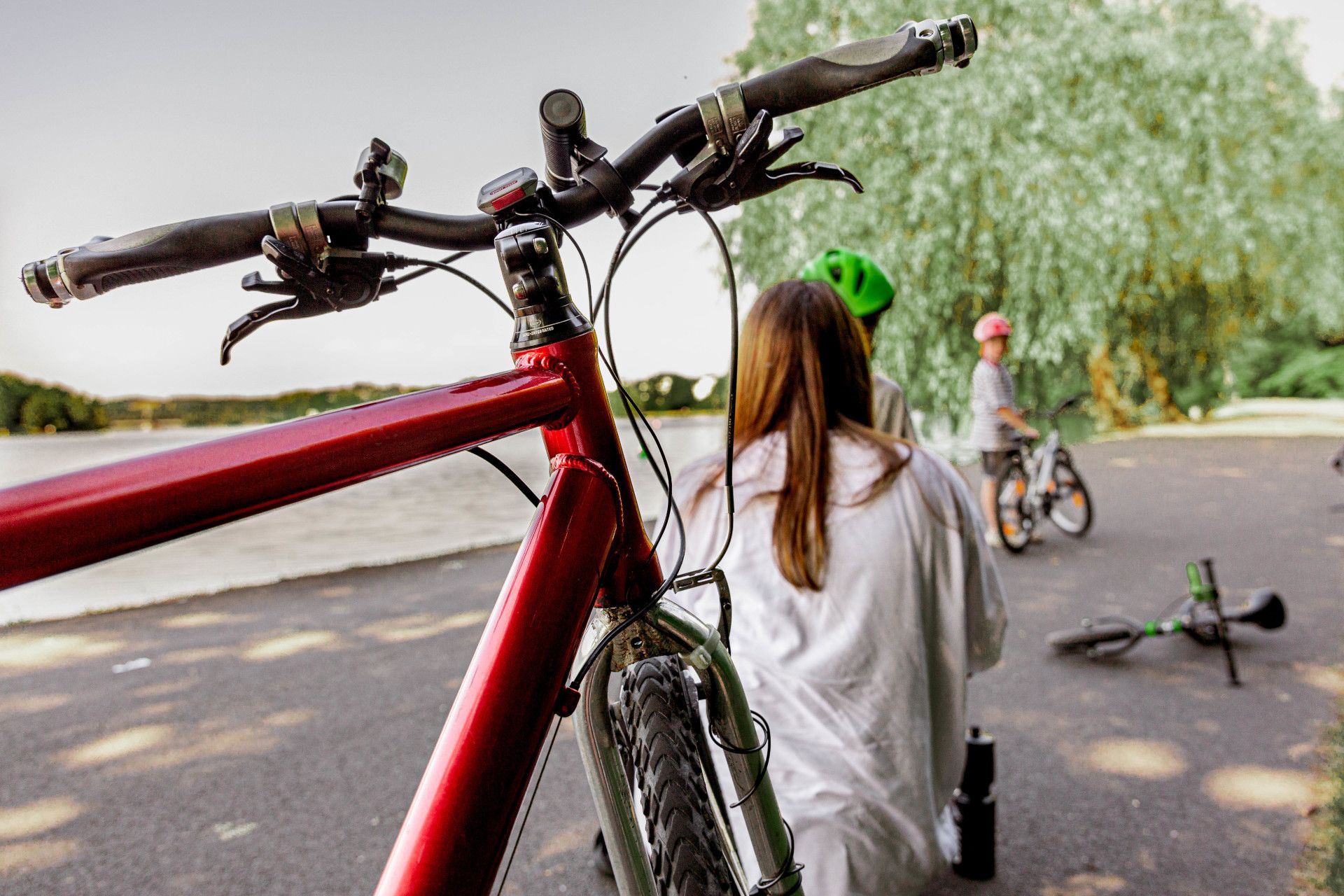 A red bicycle stands in the foreground, while a family spends time together in the background