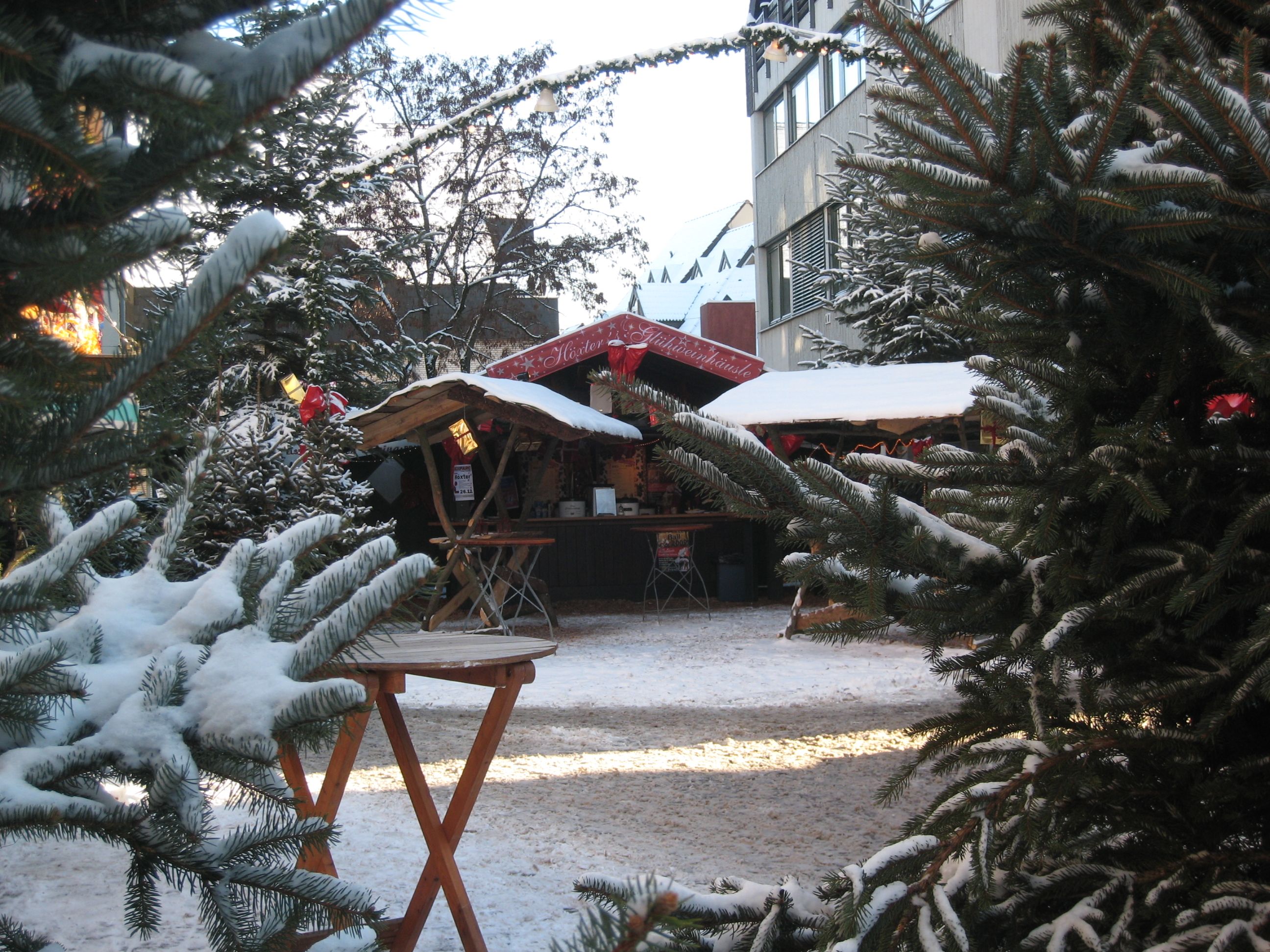 Verschneiter Weihnachtsmarkt in Höxter mit Tannenbäumen und Holzhütten.