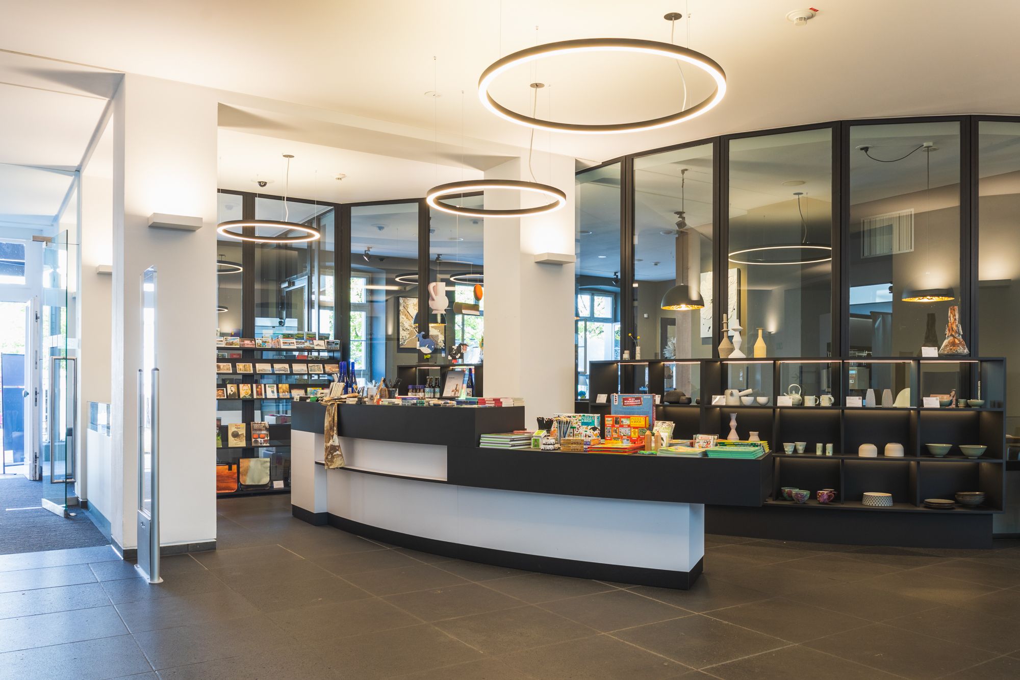 A museum shop with modern furnishings, round light fixtures, and souvenirs on the counter.