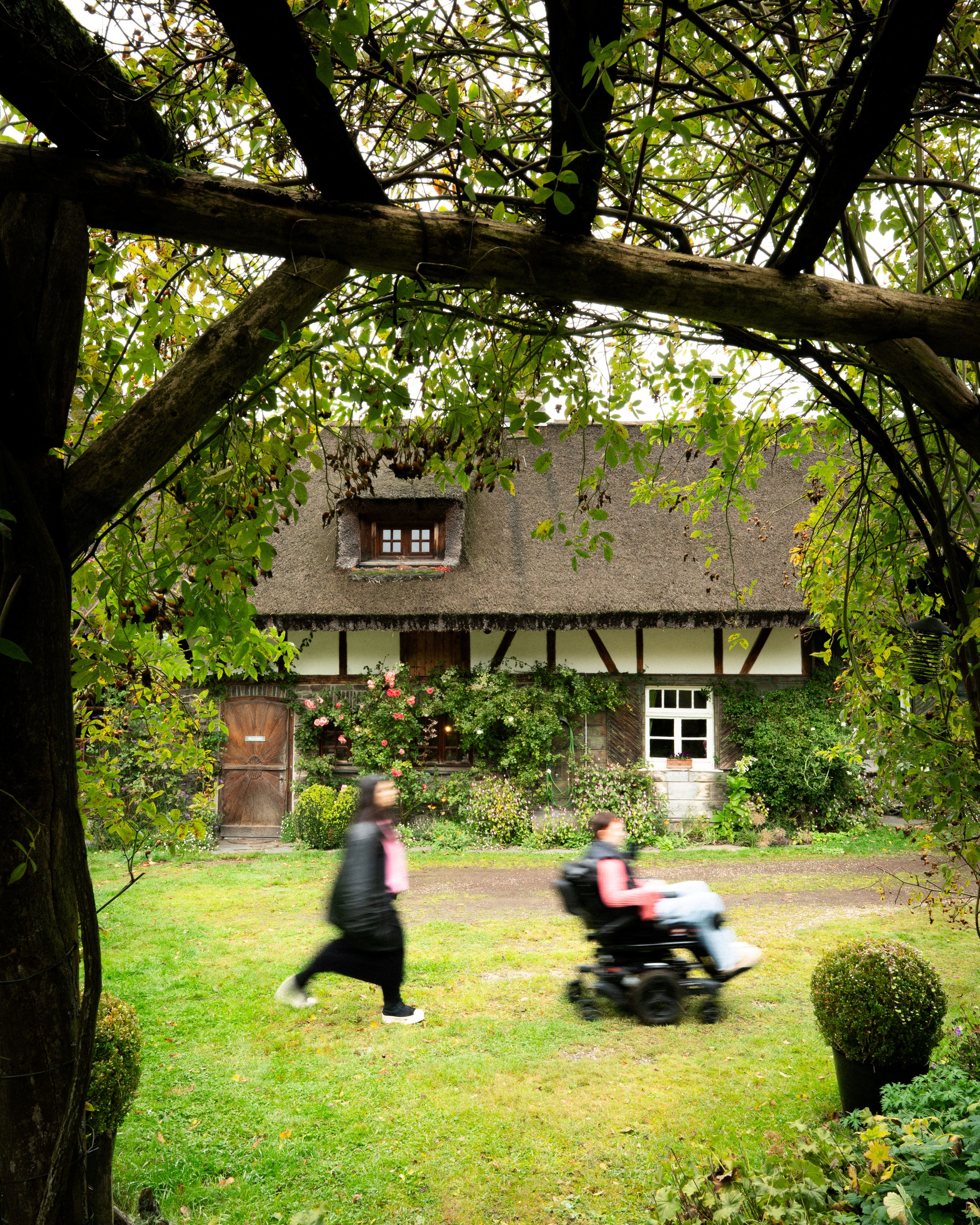 Two friends walk past a beautifully landscaped half-timbered house