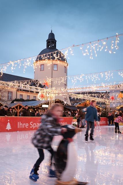 Ice skaters at the Siegen Christmas market in front of the Lower Castle, surrounded by festive fairy lights and stalls.
