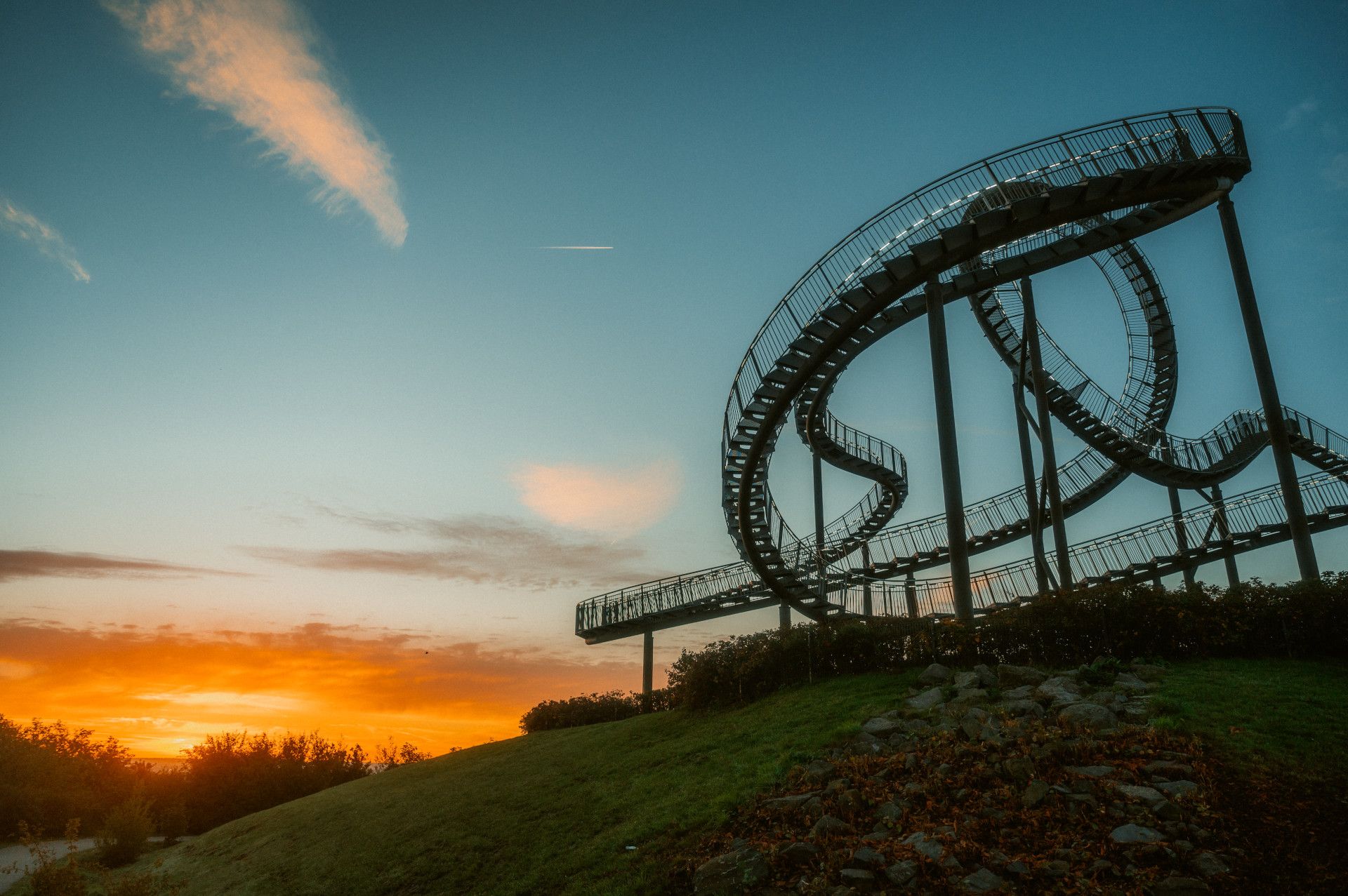 Sonnenaufgang an einem Haldenkunstwerk, das wie eine begehbare Achterbahn wirkt