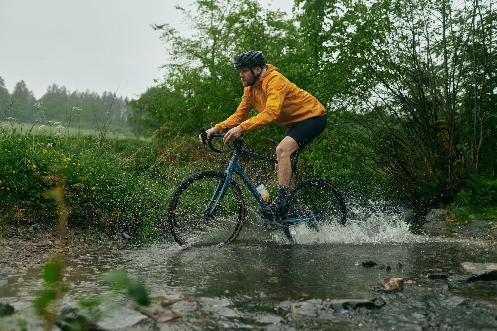A cyclist on a gravel bike crosses a puddle in the Sauerland.