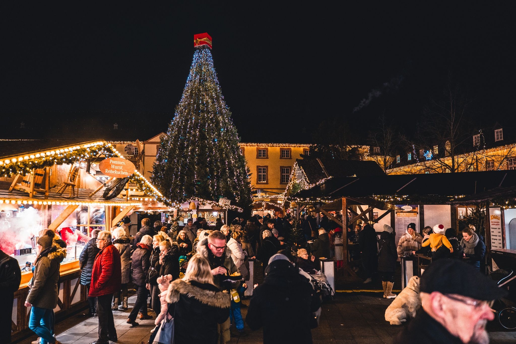 The Siegen Christmas market at the Lower Castle is well attended. A large, illuminated Christmas tree dominates the scene.