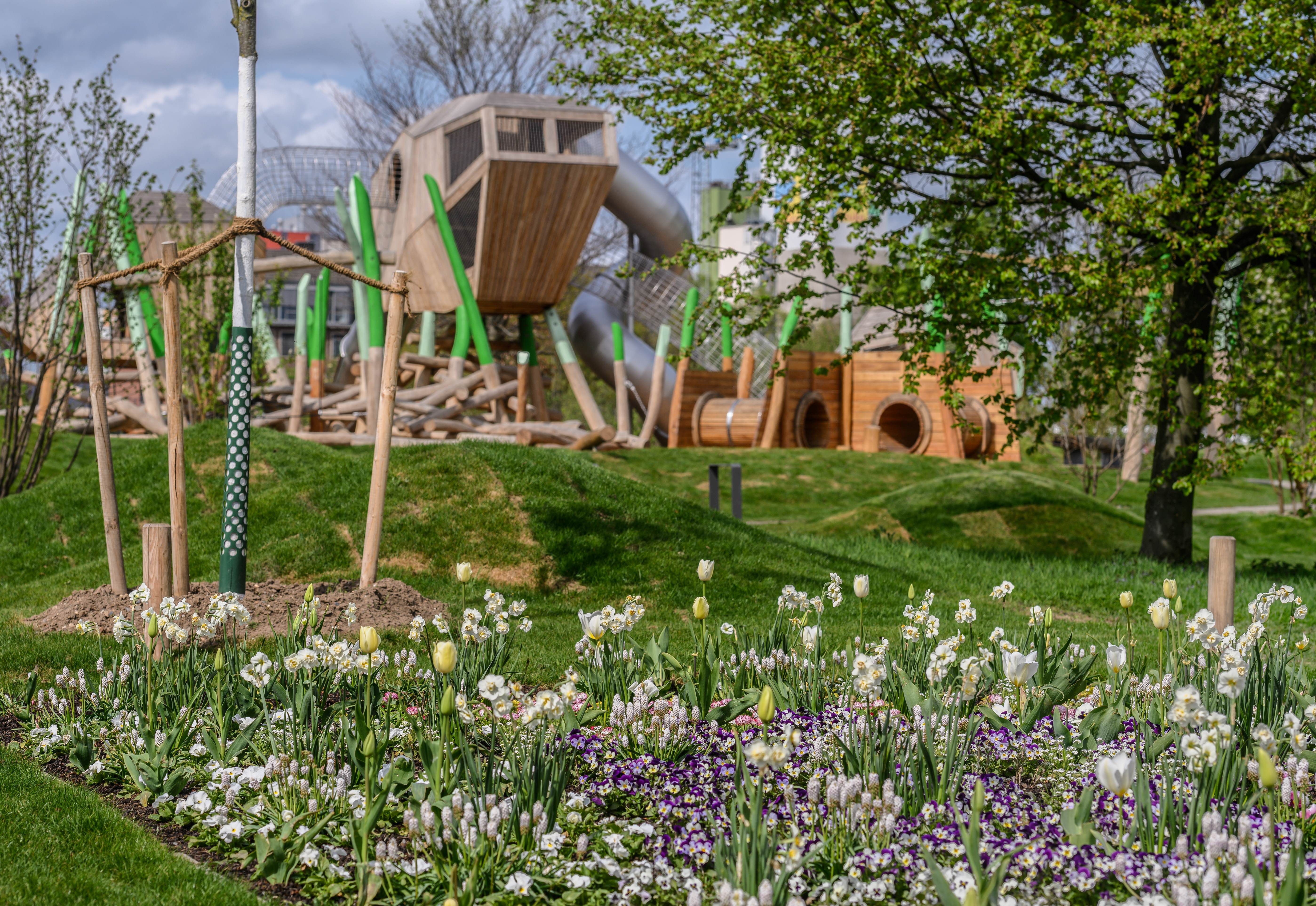 A flower bed with tulips and daffodils in front of a playground at the Neuss 2026 State Garden Show