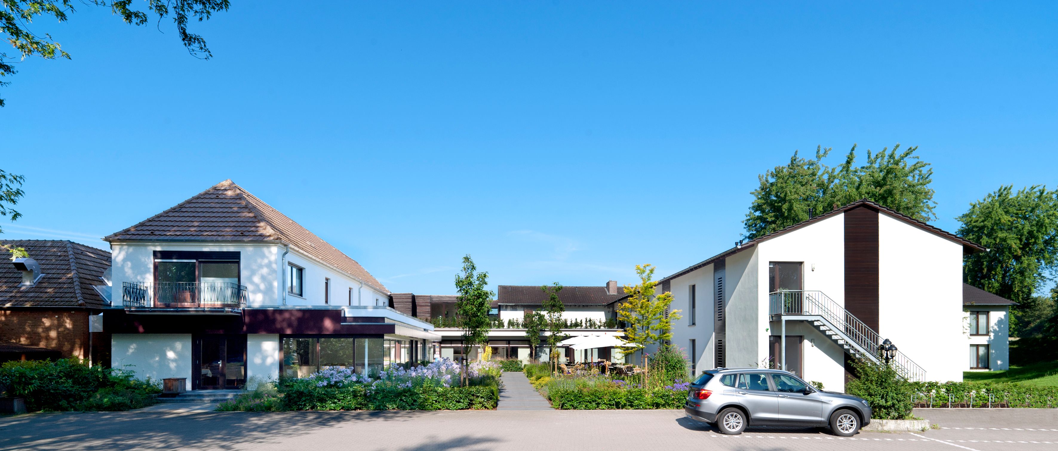 Front view of the Beckmann country house in Kalkar with garden and parked car.
