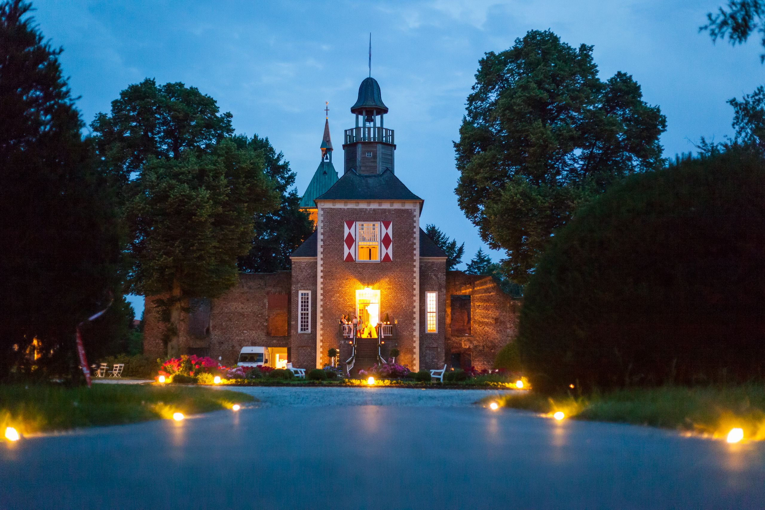 The listed building ensemble of Hertefeld Castle shines in the evening in the spotlight