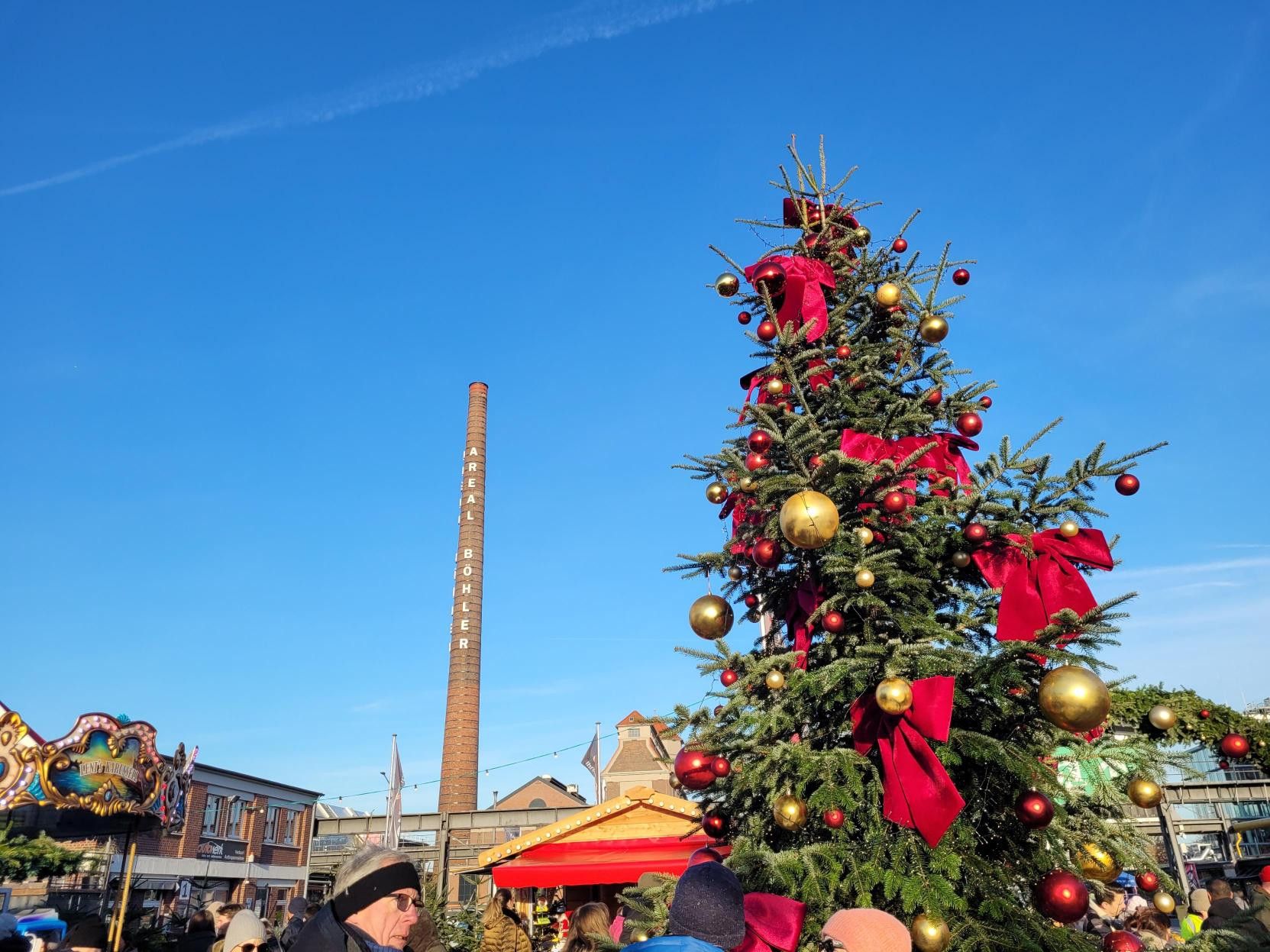 A large festively decorated Christmas tree stands in the middle of the Weihnachtszauber Areal Böhler in Düsseldorf.
