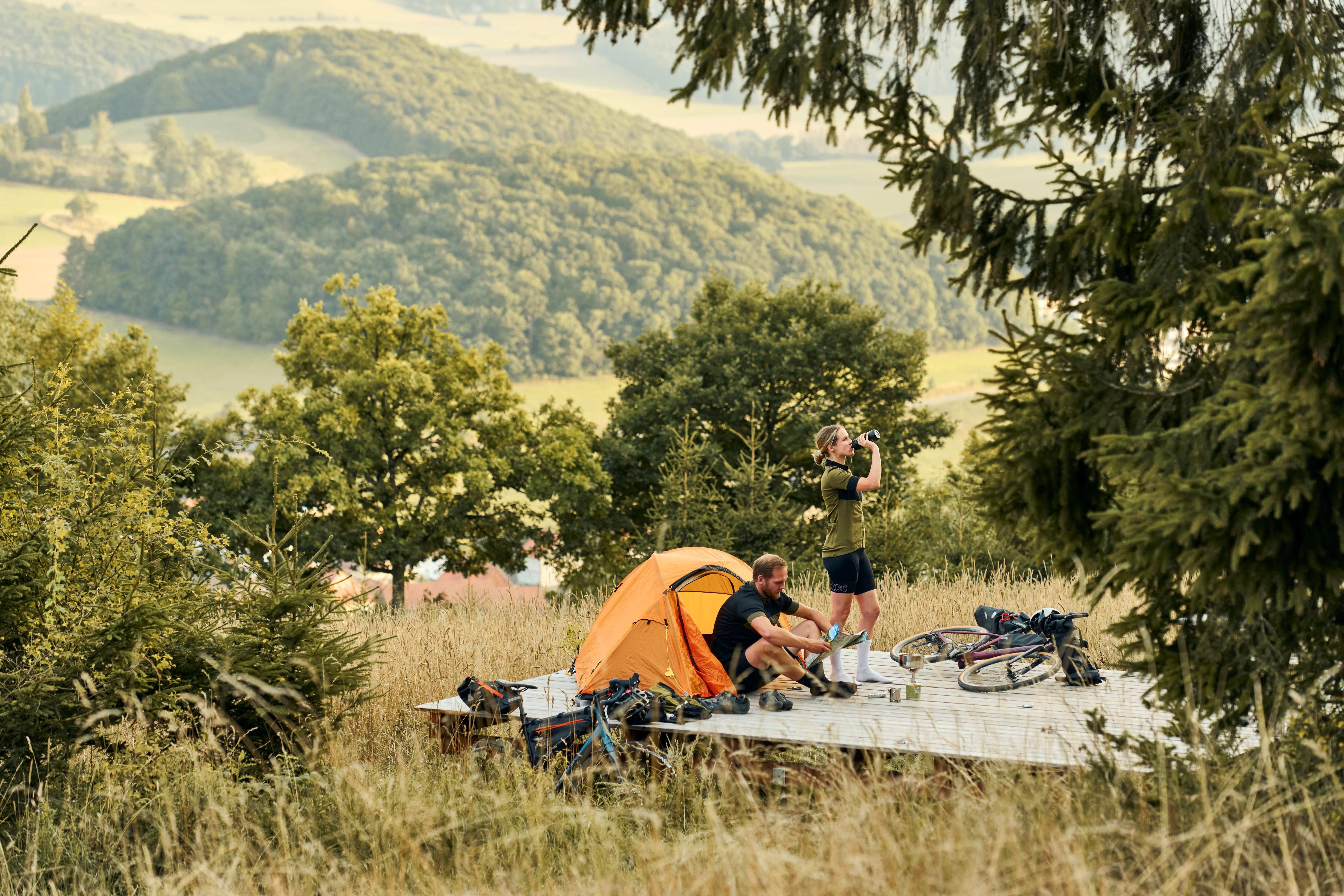 Zwei Personen haben auf Trekkingplattform Zelt aufgebaut vor Bergpanorama