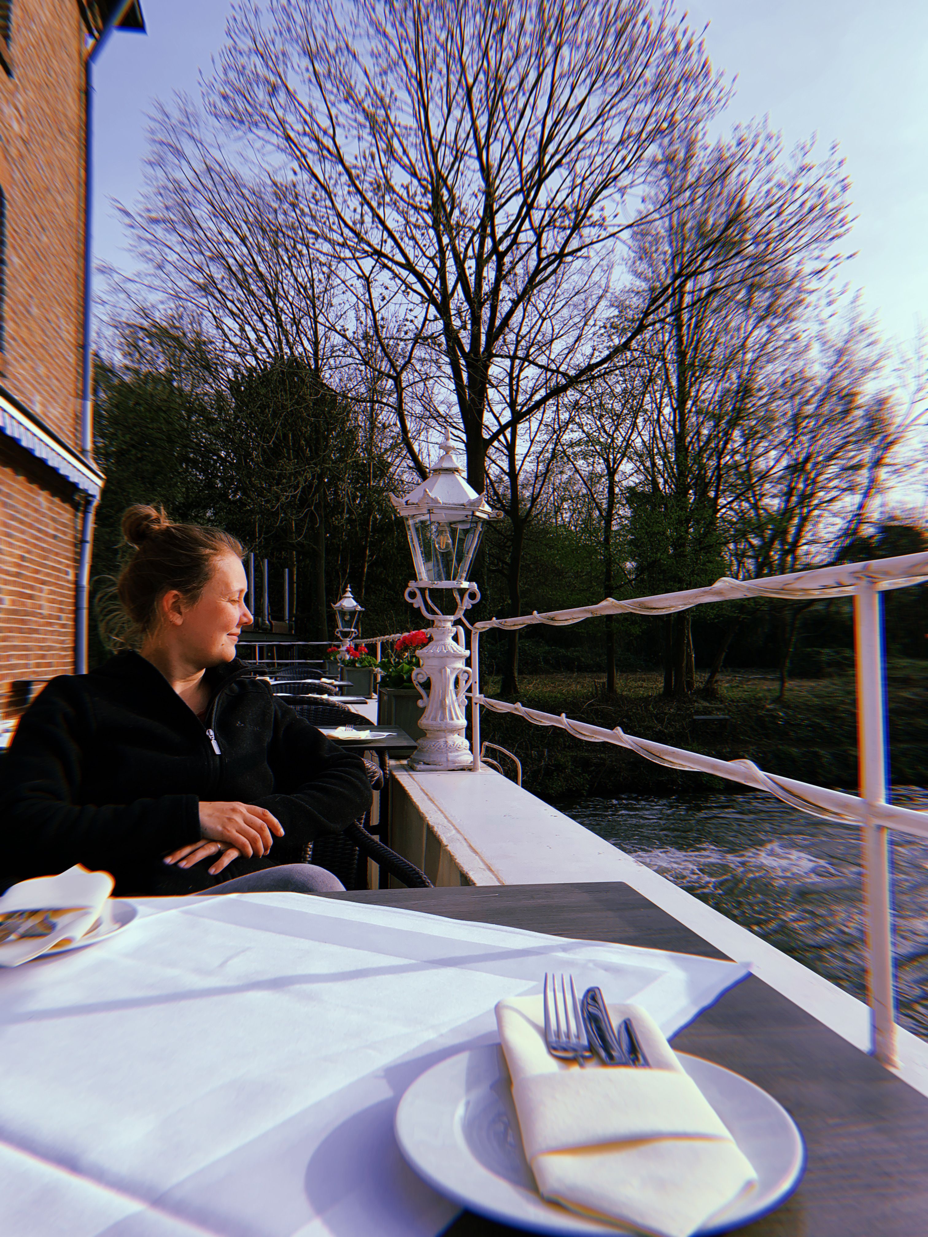 A person is sitting on the terrace of the Bedburger Mühle with their head facing the Erft river