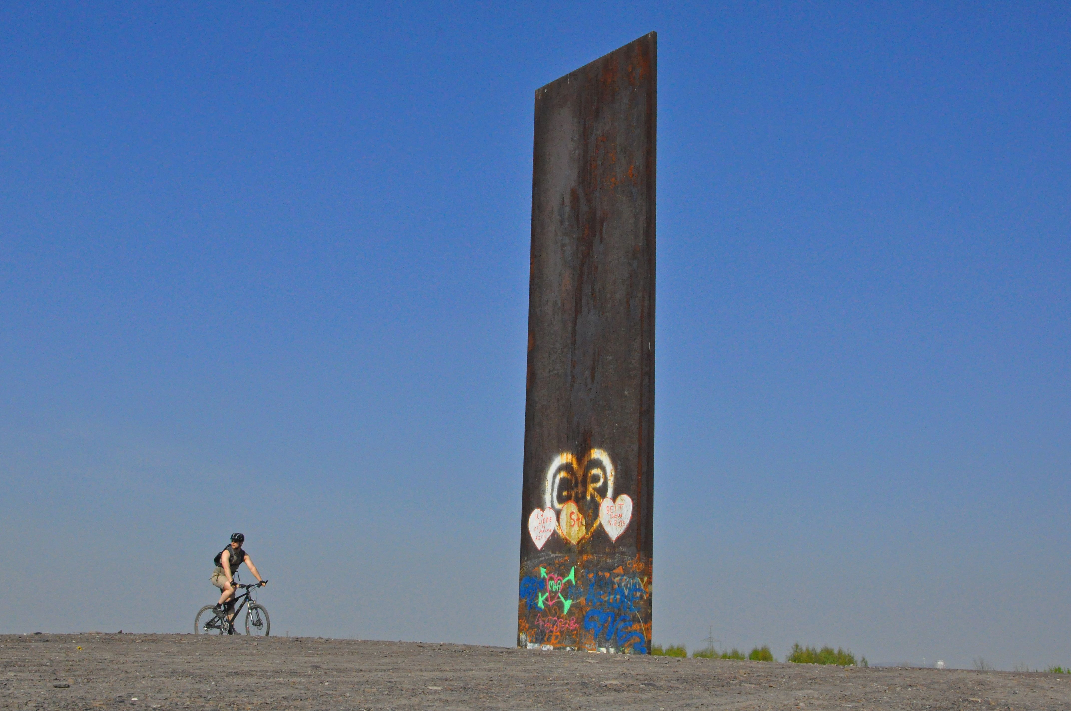 Cyclist next to a steel slab on the Schurenbachhalde in Gelsenkirchen