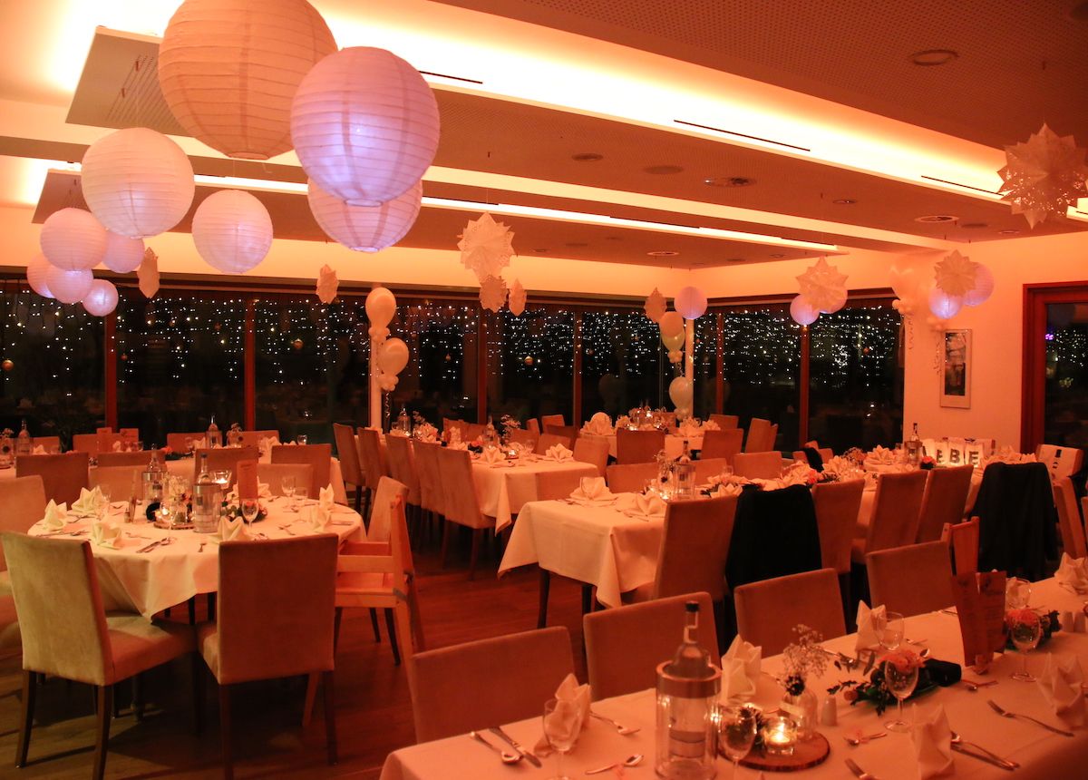 A festively decorated Kalflak room in Kalkar with round tables, white tablecloths and hanging paper lanterns.