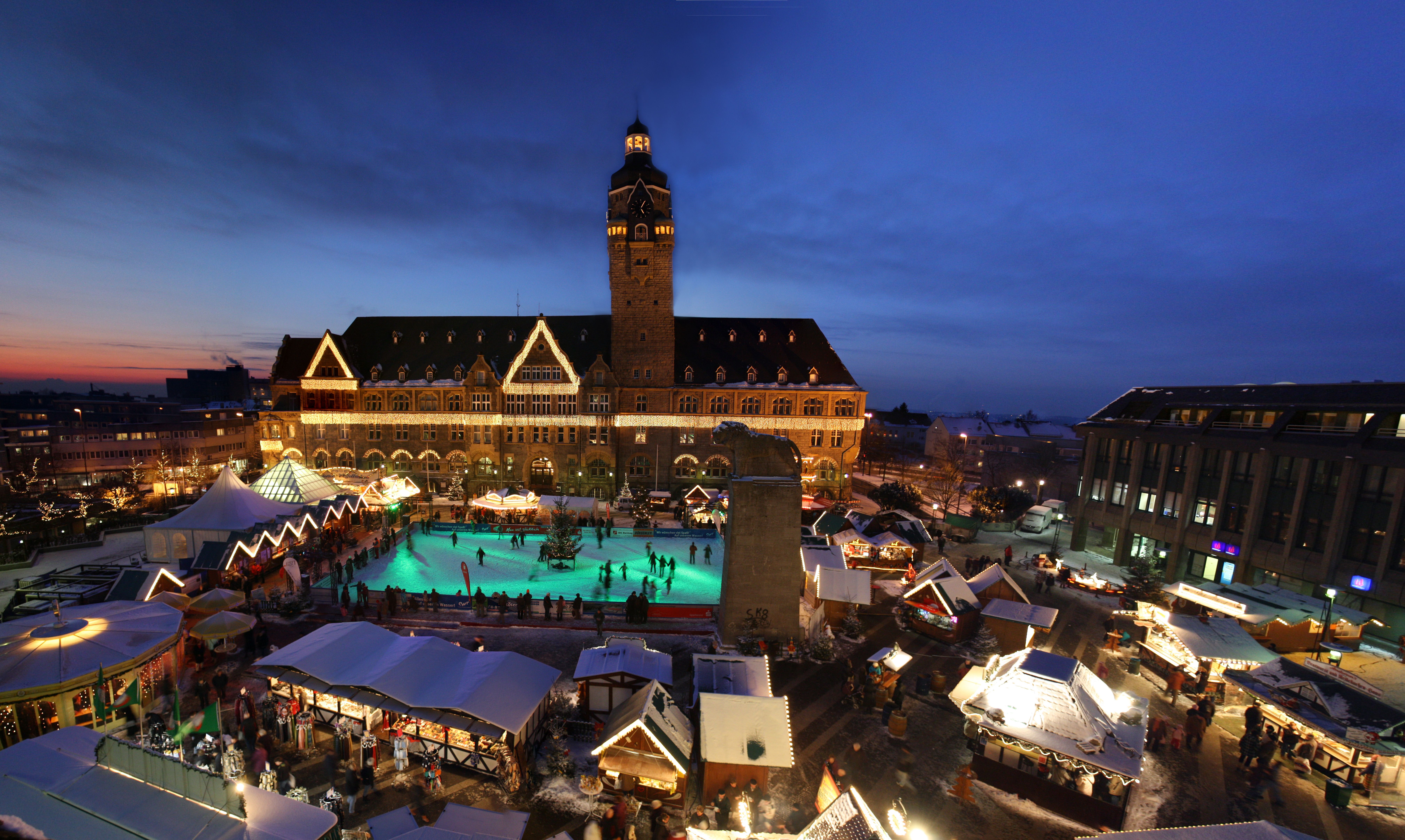 The Remscheid Christmas Market, featuring illuminated stalls, an ice rink, and the historic town hall at dusk.