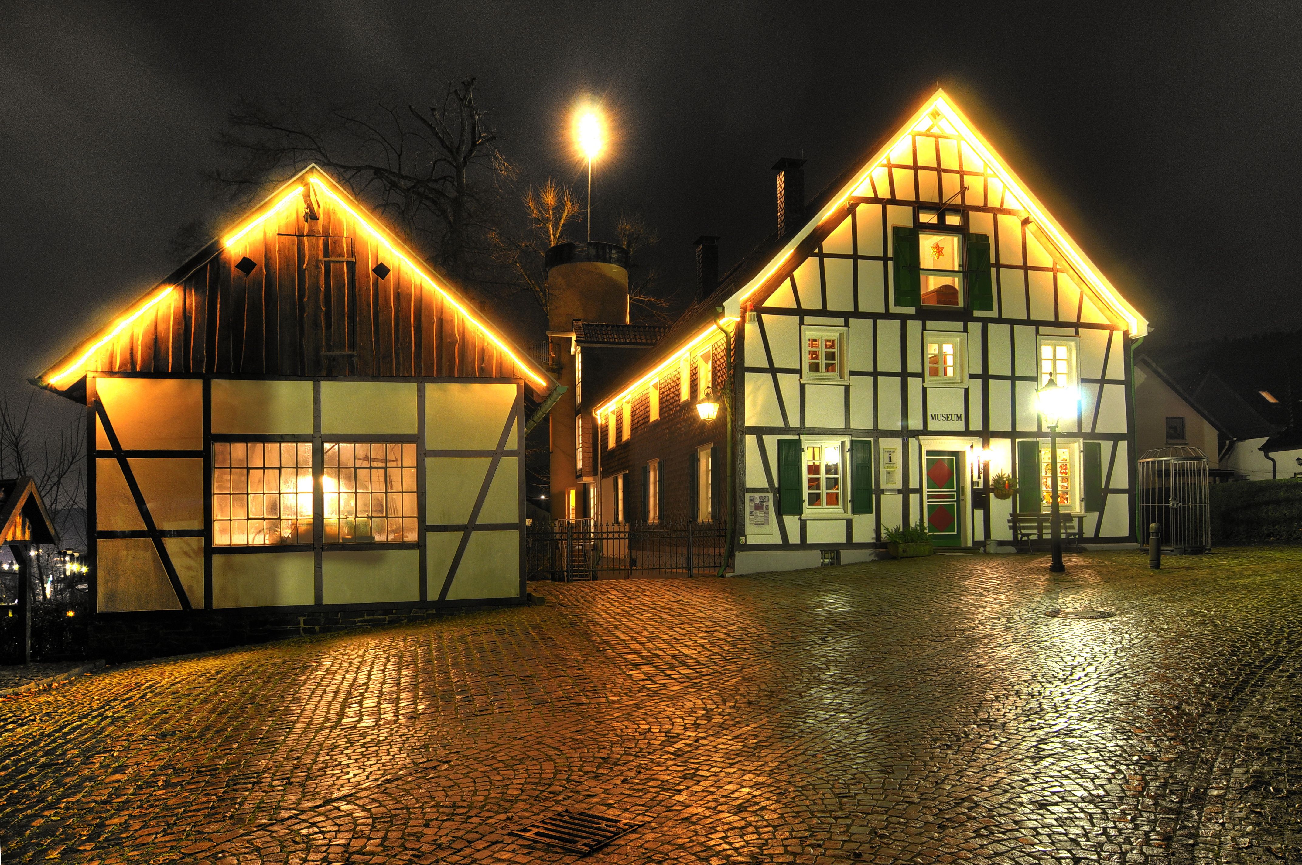 Half-timbered houses at night with festive lighting.