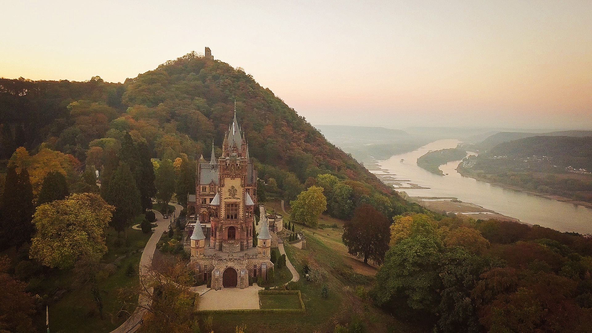 Drone shot of Drachenburg Castle with Drachenfels and the Rhine in the background