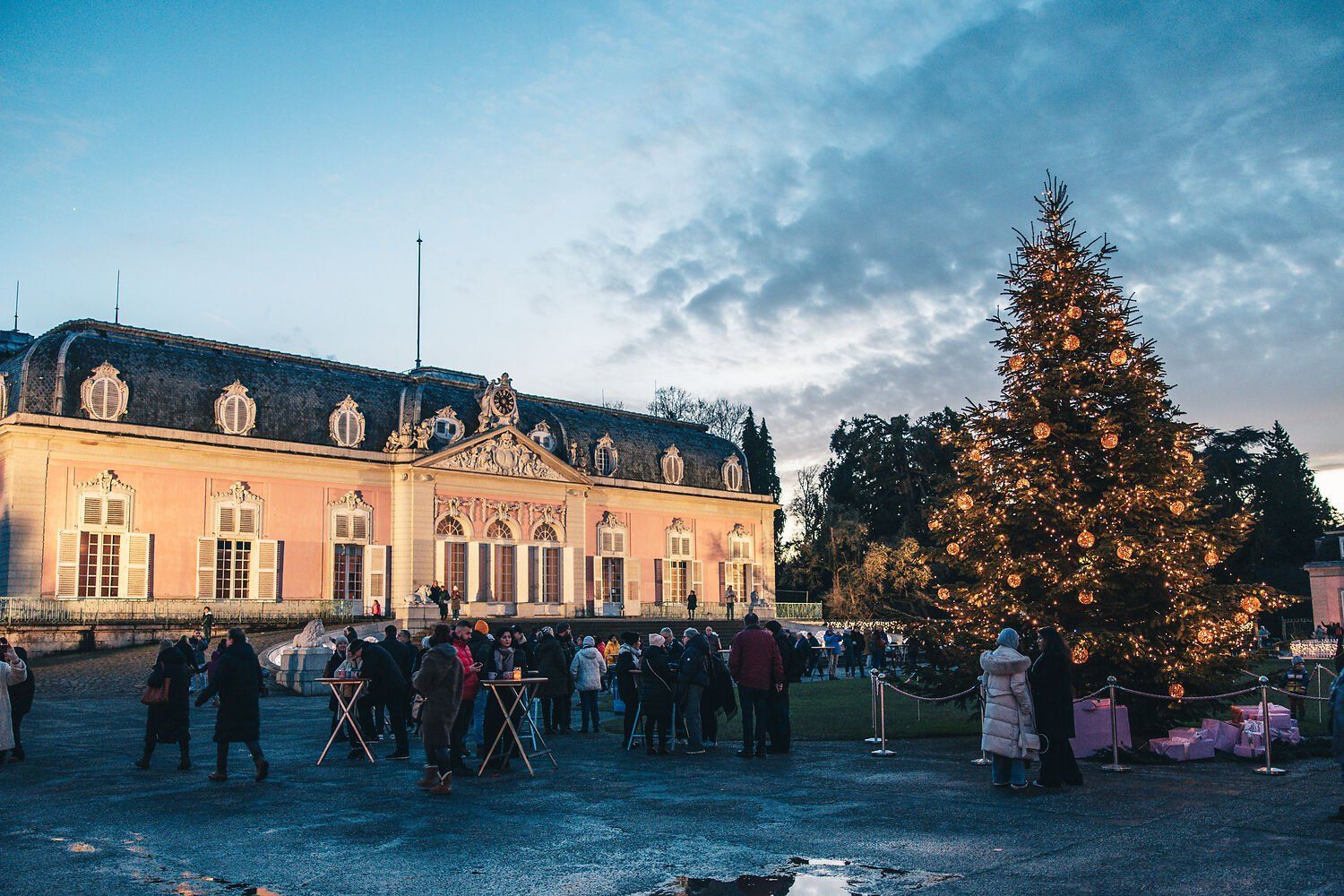 Christmas market at Benrath Palace, featuring a large, lit-up Christmas tree and visitors in front of the Baroque palace.