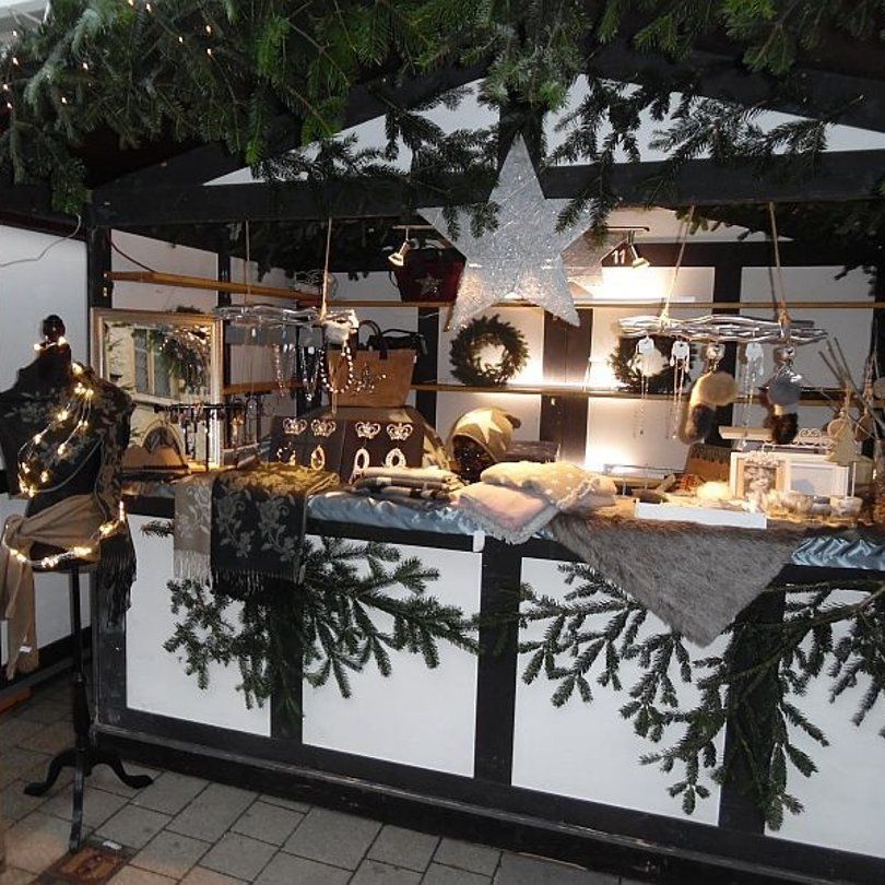 A festively decorated Christmas market stall with jewelry, scarves and decorations.