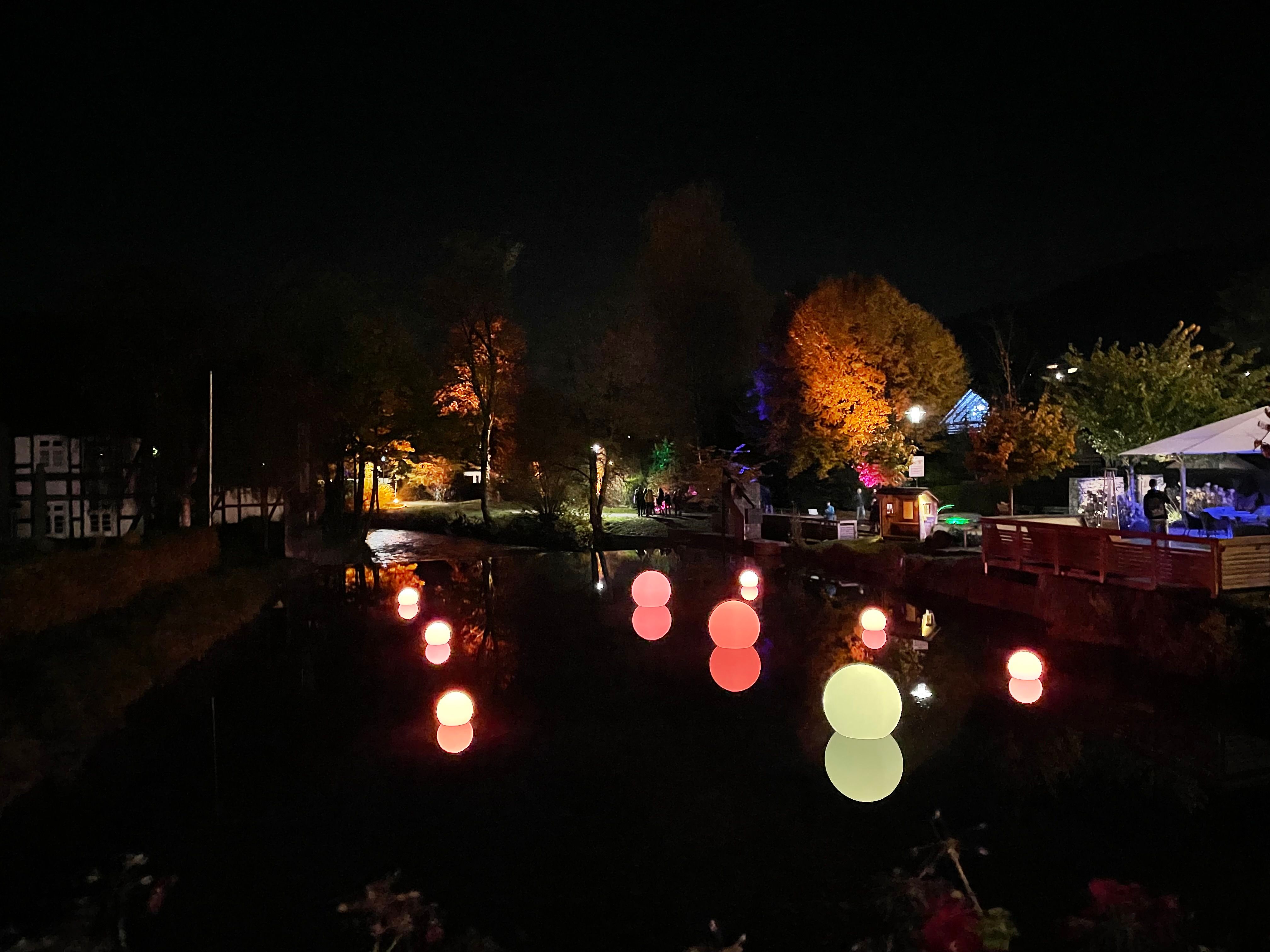 Glowing spheres float on a river at night in Lennestadt.