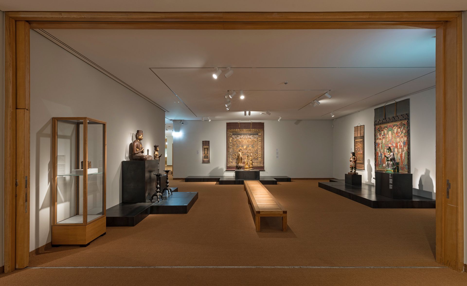 A view of a gallery at the Museum of East Asian Art featuring Buddhist artworks from East Asia, including sculptures, ritual objects, and hanging scrolls