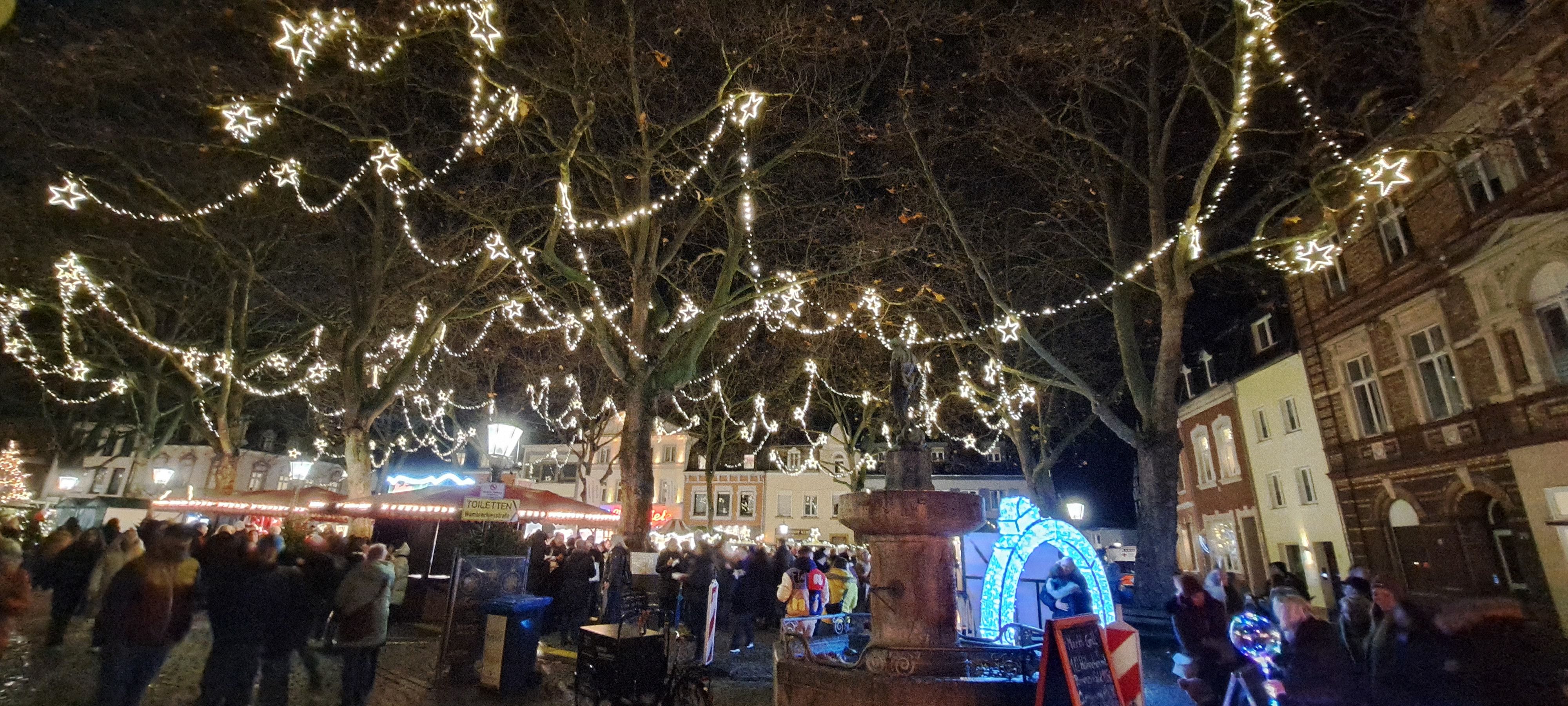 Star-shaped fairy lights illuminate the Christmas market in Kempen at night and create a festive atmosphere.
