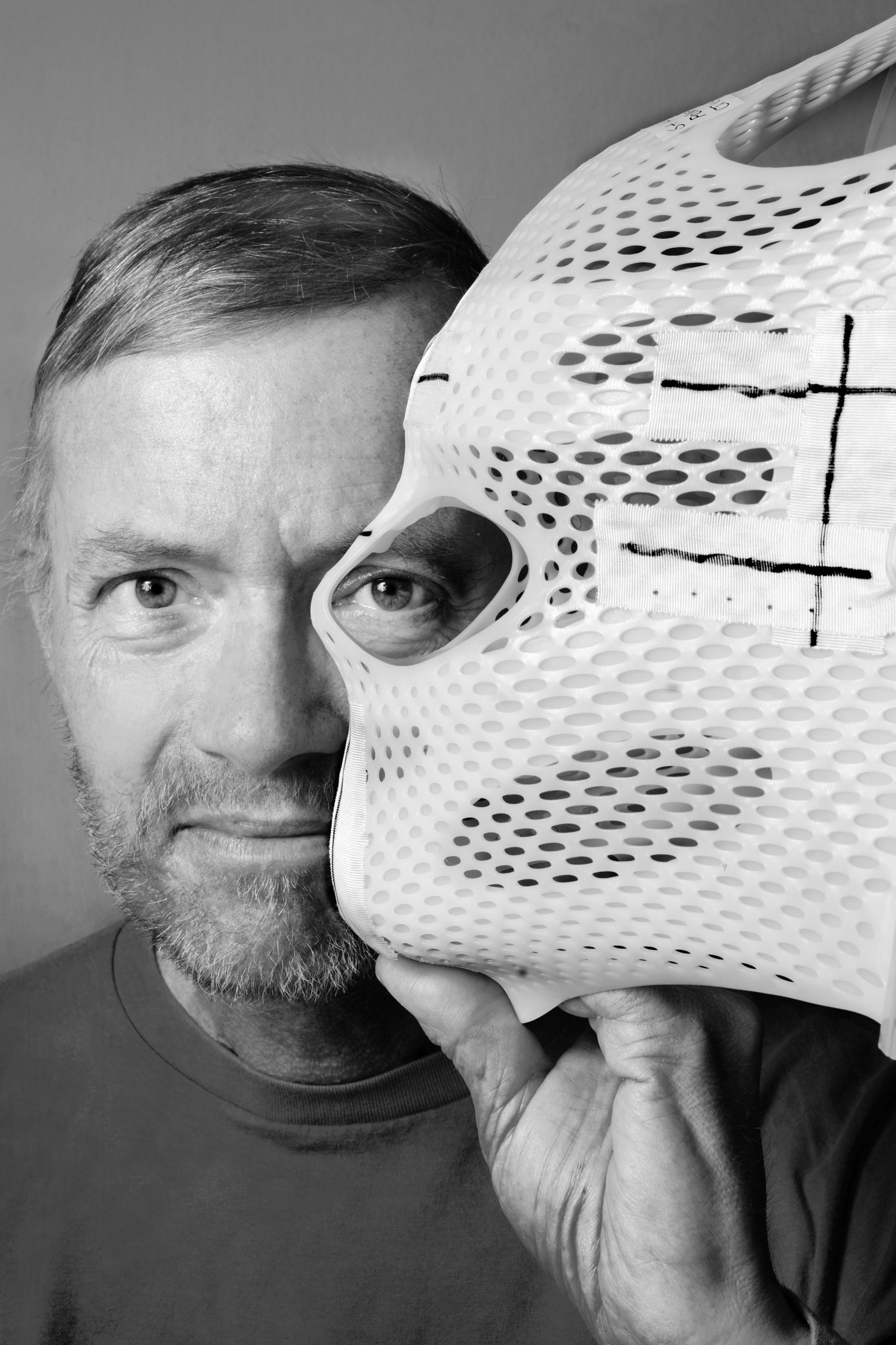 Herlinde Koelbl's portrait shows a patient wearing his custom-made thermoplastic mask. The crosshairs drawn on it serve as a vital guide during radiation therapy, ensuring treatment with millimeter precision.